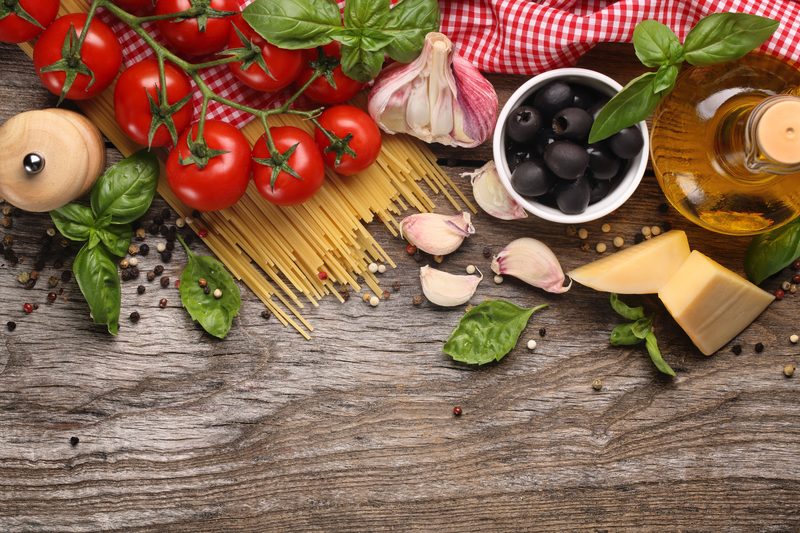 Tomatoes, spaghetti, garlic, olives, basil, cheese and olive oil on a wooden table